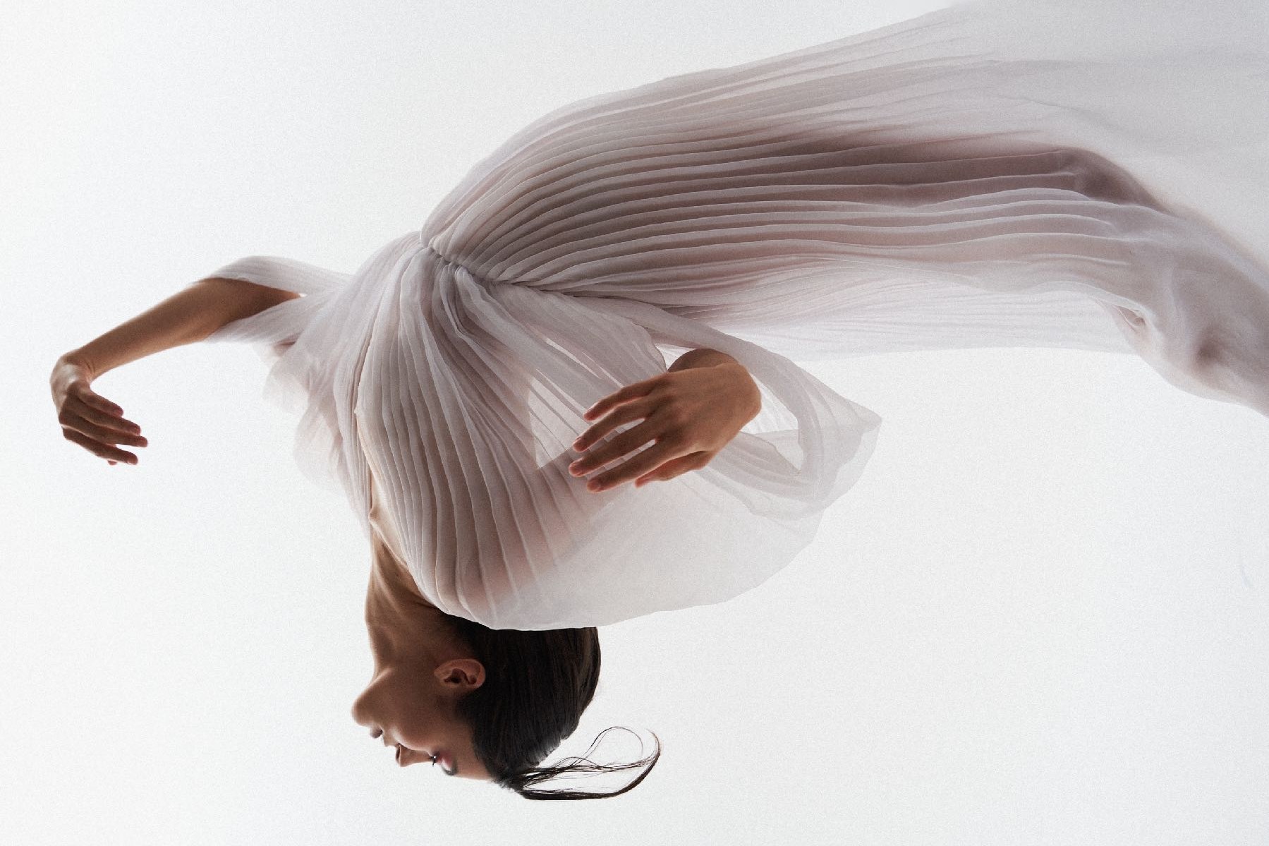 Dancer in pleated white fabric, suspended in motion